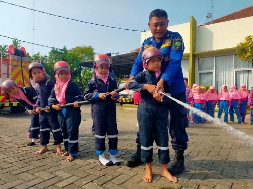 SIMULASI: Petugas Damkar Satpol PP Blora saat mengajari anak-anak SD Islam Baitunnur Blora memadamkan api menggunakan selang.